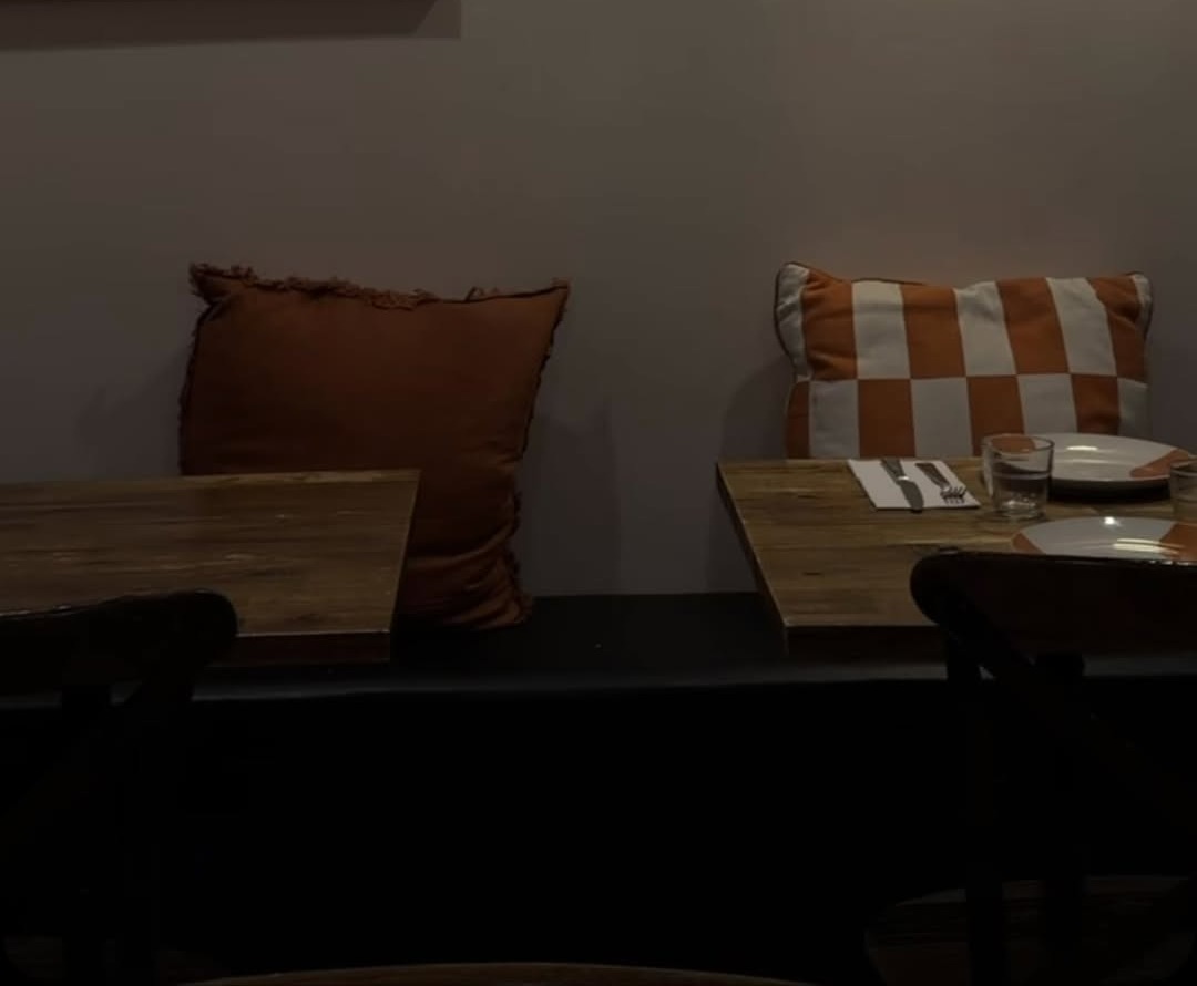 Timber tables set for dinner with terracotta and checked cushions