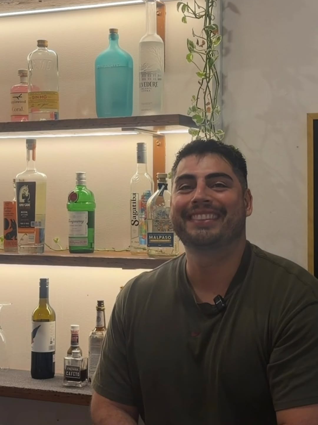 A member of the Big Papi’s team seated at the bar in front of the lit spirit shelves